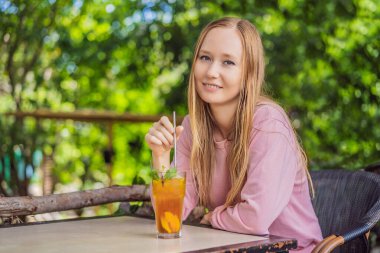 Yeniden kullanılabilir paslanmaz çelik pipet kullanarak meyve çayı içen çevre dostu bir kadın.