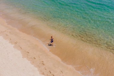 Sahilde koşan bir koşucu okyanus manzaralı. Kardiyo antrenmanı yapan kadın sporcu sabah antrenmanı yapıyor. Kahraman hava aracı görüntüsü, bir sürü kopya alanı