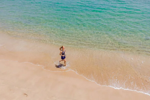 Futó fut a tengerparton az óceán - kilátás felülről. Női atléta edz kardio kocogás közben reggeli edzés. Hero légi drón nézet lövés, sok másolási hely — Stock Fotó
