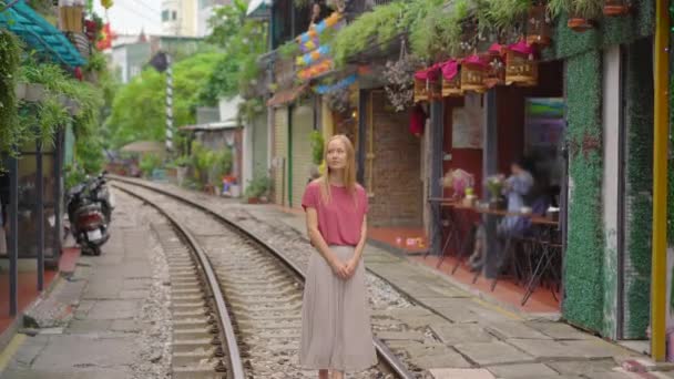 La joven viajera explora la zona de la ciudad de Hanoi donde los caminos del ferrocarril pasan por una zona residencial. Hanoi Train Street es un famoso destino turístico — Vídeos de Stock