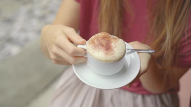 若い女性旅行者は、ハノイ市内の住宅地を通る鉄道のパスに座って人気のある卵コーヒーを飲みます。ハノイ電車街は有名な観光地です — ストック動画