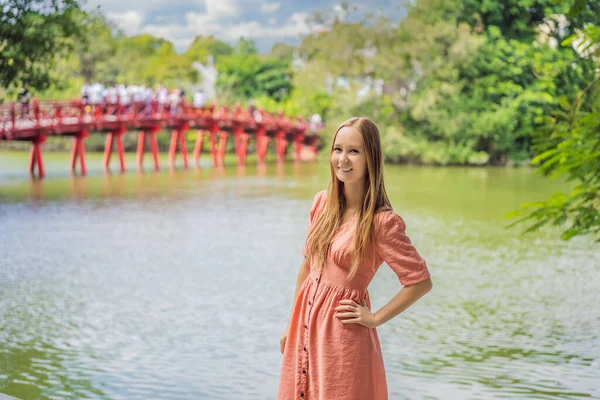 Kaukaska kobieta podróżnik na tle Red Bridge w ogrodzie parku publicznego z drzewami i refleksji w środku Hoan Kiem Lake w centrum Hanoi. Wietnam otwiera się ponownie po kwarantannie koronawirusów — Zdjęcie stockowe