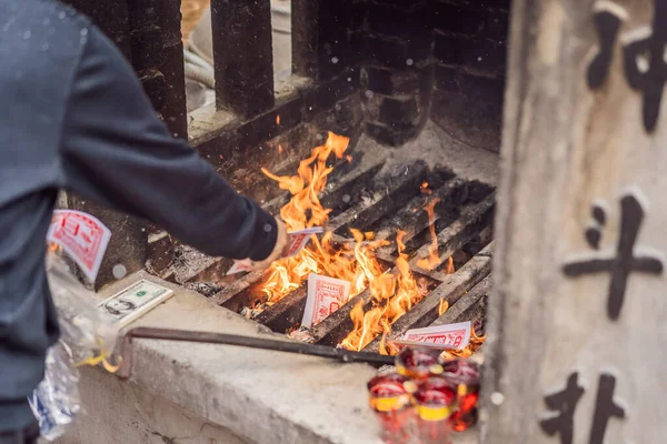 Burning the silver and gold fake money paper for Chinese dead people ancestors. Joss paper money burning metal bucket dead in Chinese new year