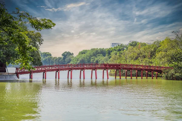 El puente rojo en el jardín del parque público con árboles y reflexión en el centro del lago Hoan Kiem en el centro de Hanoi. Ciudad urbana al atardecer, Vietnam. Fondo de paisaje urbano —  Fotos de Stock