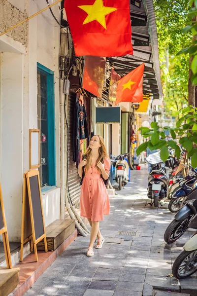 Turista donna con zaino cammina su strada vietnamita con bandiere. Il Vietnam riapre dopo la quarantena del coronavirus COVID 19 — Foto Stock