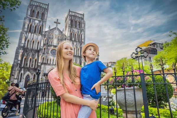 Ung mamma och son turister på bakgrund av St Josephs Cathedral i Hanoi. Vietnam återupptas efter karantänen för coronavirus COVID 19 — Stockfoto
