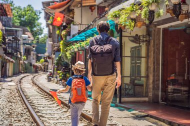 Baba ve oğul gezginler Hanoi şehrindeki yerleşim alanlarından geçen demiryolu yollarında yürürler. Hanoi Tren Sokağı ünlü bir turizm merkezidir. Vietnam, koronavirüs karantinasından sonra yeniden açıldı