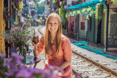 Genç bayan gezgin kahve içiyor Hanoi şehrinin yerleşim alanından geçen tren yolunun kenarında oturuyor. Hanoi Tren Sokağı ünlü bir turizm merkezidir. Vietnam Coronavirüs 'ten sonra yeniden açılıyor.