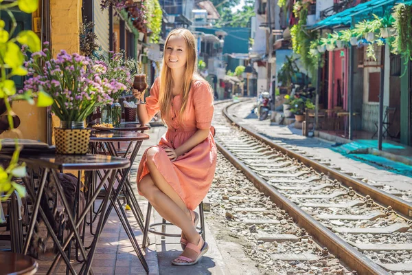 Ung kvinna resenär dricker kaffe sitter vid järnvägsvägarna som går genom bostadsområde i Hanoi stad. Hanoi Train Street är ett känt turistmål. Vietnam öppnas på nytt efter coronavirus — Stockfoto