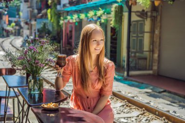 Genç bayan gezgin kahve içiyor Hanoi şehrinin yerleşim alanından geçen tren yolunun kenarında oturuyor. Hanoi Tren Sokağı ünlü bir turizm merkezidir. Vietnam Coronavirüs 'ten sonra yeniden açılıyor.