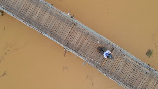 Aereo rallentamento girato di un ponte di legno attraverso il fiume in Asia con moto in sella su di esso. Concetto di costruzione di trasporti pericolosi — Video Stock