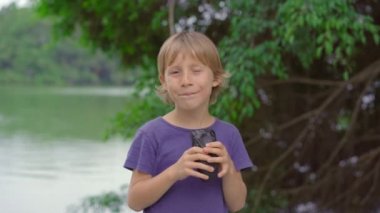 Gölün kenarında duran küçük çocuk yeni popüler Vietnam sokak yemekleri olan siyah banh mi yiyor. Vietnam 'a seyahat