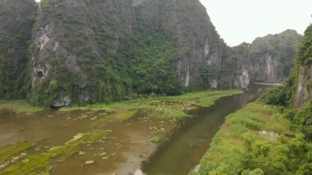 Foto aérea de hermosas montañas de piedra caliza con pasos tallados por un río en la región de Ninh Binh, un famoso destino turístico en el norte de Vietnam. Viajar a Vietnam concepto — Vídeo de stock