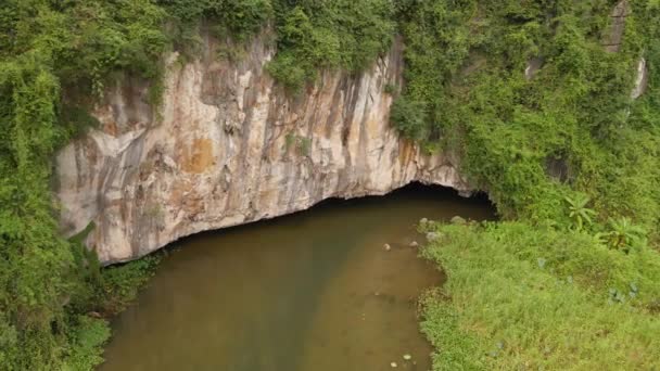 Zdjęcie lotnicze pięknych gór wapiennych z przełęczami rzeźbionymi nad rzeką w rejonie Ninh Binh, słynnej miejscowości turystycznej w północnym Wietnamie. Podróż do Wietnamu. Wejście do jaskini, która — Wideo stockowe