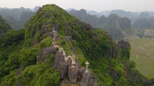 Colpo aereo di turista uomo dal monumento drago sulla cima della montagna di marmo, Mua Cave montagna, a Ninh Binh, una destinazione turistica nel nord del Vietnam. Viaggio in Vietnam concetto — Video Stock