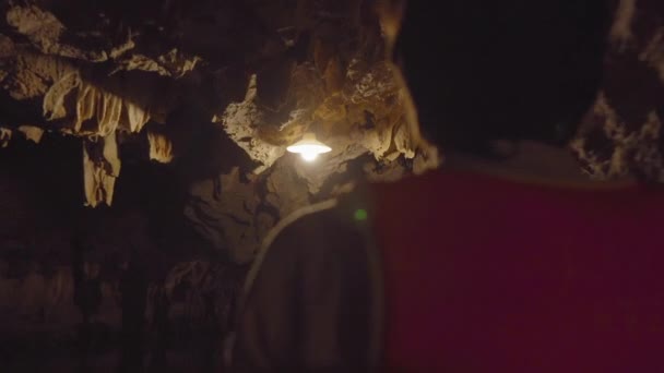 Närbild skott av en ung man i en båt som rör sig genom en grotta snidade genom ett berg i kalksten stenar område i Ninh Binh, ett turistmål i norra Vietnam. Resor till Vietnam konceptet — Stockvideo