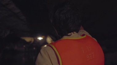 Kuzey Vietnam 'da turistik bir yer olan Ninh Binh' deki bir kireçtaşı kayalıklarındaki bir mağaradan geçen kayıktaki genç bir adamın yakın çekimi. Vietnam 'a seyahat