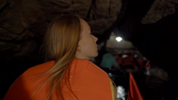 Primer plano de una mujer joven en un barco que se mueve a través de una cueva tallada a través de una montaña en la zona de rocas de piedra caliza en Ninh Binh, un destino turístico en el norte de Vietnam. Viajar a Vietnam concepto — Vídeo de stock