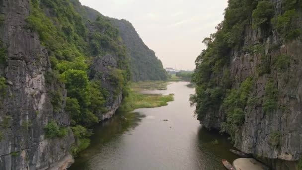 Zdjęcie lotnicze pięknych gór wapiennych z przełęczami rzeźbionymi nad rzeką w rejonie Ninh Binh, słynnej miejscowości turystycznej w północnym Wietnamie. Podróż do Wietnamu — Wideo stockowe