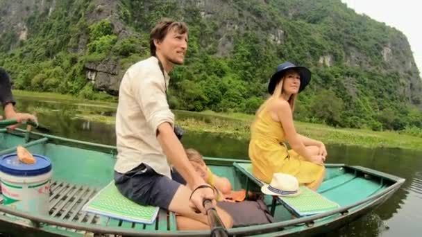 En ung familj på en båt som har en flod resa bland spektakulära kalksten stenar i Ninh Binh, ett turistmål i norra Vietnam. Resor till Vietnam konceptet — Stockvideo