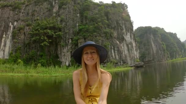 在越南北部的一个旅游胜地宁滨，一名年轻女子坐在一条船上，在壮观的石灰岩中沿河漂流。前往越南的旅行概念 — 图库视频影像
