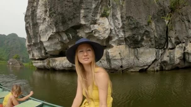 Uma jovem mulher em um barco que tem uma viagem fluvial entre rochas calcárias espetaculares em Ninh Binh, um destino turístico no norte do Vietnã. Viajar para Vietnã conceito — Vídeo de Stock