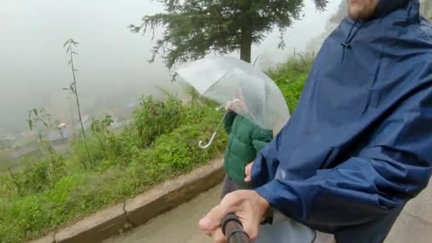 Um jovem e seu filho caminham em um vale Cat Cat sob chuva. Sa Pa, Vietname do Norte. Viajar para Vietnã conceito — Vídeo de Stock