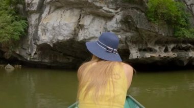 Kuzey Vietnam 'da turistik bir yer olan Ninh Binh' de muhteşem kireçtaşı kayaları arasında nehir gezisi yapan genç bir adam. Vietnam 'a seyahat