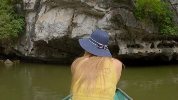 在越南北部的一个旅游胜地宁滨，一名年轻男子在一条船上，在壮观的石灰岩中游览河流。前往越南的旅行概念 — 图库视频影像