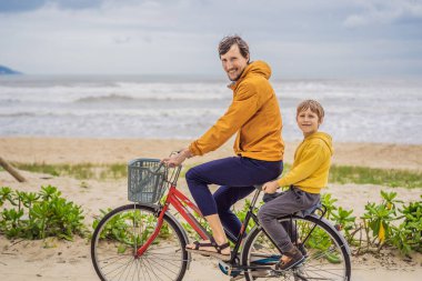 Baba ve oğlu, güzel bir manzarada, bir yaz gününde bisikletle hafta sonu gezintisine çıkıyorlar.