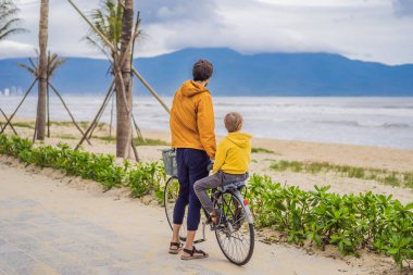Baba ve oğlu, güzel bir manzarada, bir yaz gününde bisikletle hafta sonu gezintisine çıkıyorlar.