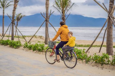 Baba ve oğlu, güzel bir manzarada, bir yaz gününde bisikletle hafta sonu gezintisine çıkıyorlar.