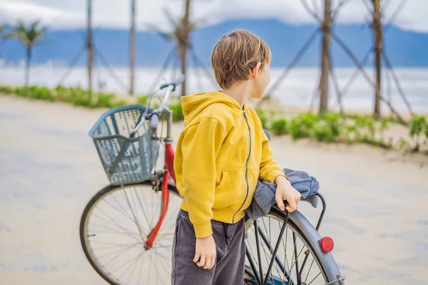 Активний блондин хлопчик їде на велосипеді в парку біля моря. Дитина Тоддлер мріє і веселиться в теплий літній день. ігри на відкритому повітрі для дітей — стокове фото