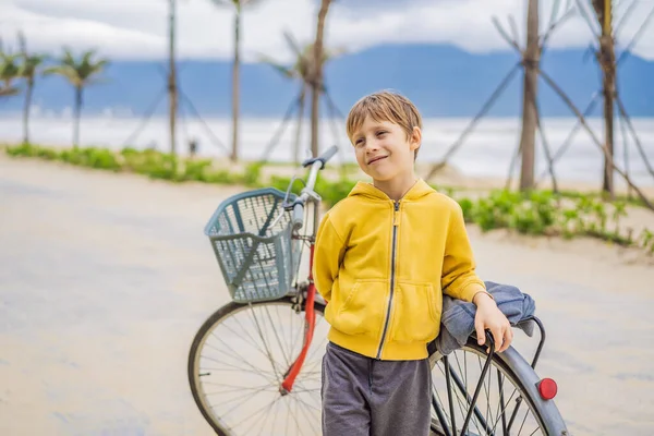 Aktivní blonďatý kluk řídí kolo v parku u moře. Dítě batole sní a baví se v teplý letní den. venkovní hry pro děti — Stock fotografie