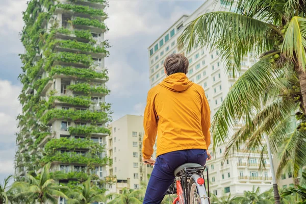 男はエコアーキテクチャを見ている。ファサードの水耕栽培植物と緑のカフェ。生態系と緑の都市、都市環境の概念に住んでいる。近代的な建物覆われた緑の植物 — ストック写真