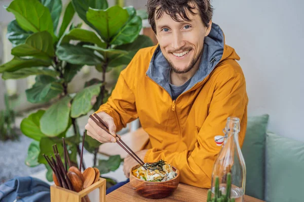 Man eating Raw Organic Poke Bowl with Rice and Veggies close-up on the table. Top view from above horizontal — Stock Photo, Image