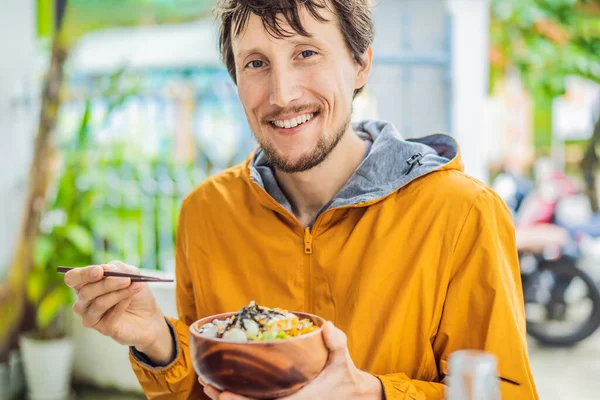 Man eating Raw Organic Poke Bowl with Rice and Veggies close-up on the table. Vista superior de cima horizontal — Fotografia de Stock