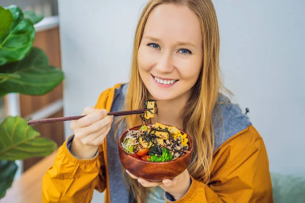 Жінка їсть Raw Organic Poke Bowl з Rice and Veggies на столі. Верхній вид згори. — стокове фото