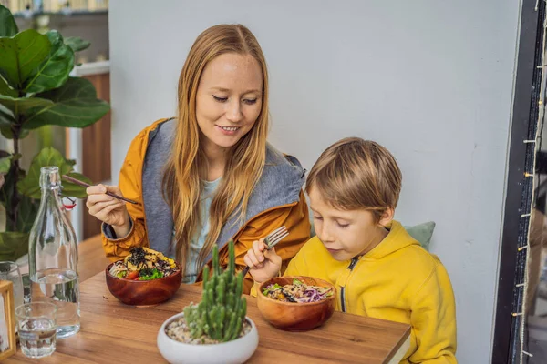 Mor och son äter rå ekologisk Poke skål med ris och grönsaker närbild på bordet. Ovanifrån horisontellt — Stockfoto