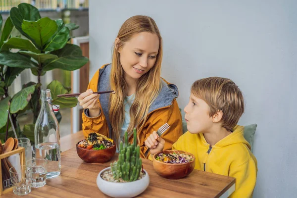 Mother and son eating Raw Organic Poke Bowl with Rice and Veggies close-up on the table. Top view from above horizontal — Stock Photo, Image