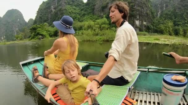 在越南北部的一个旅游胜地宁滨，一个年轻的家庭坐在一条船上，在壮观的石灰岩中渡河。前往越南的旅行概念 — 图库视频影像
