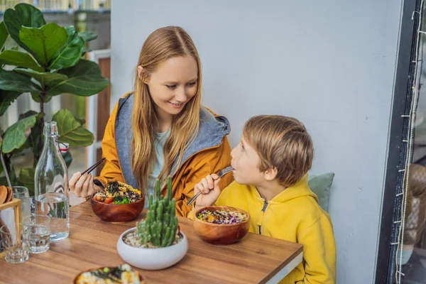 Mother and son eating Raw Organic Poke Bowl with Rice and Veggies close-up on the table. Top view from above horizontal — Stock Photo, Image