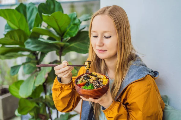 Жінка їсть Raw Organic Poke Bowl з Rice and Veggies на столі. Верхній вид згори. — стокове фото