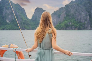 Elbiseli çekici bir kadın Halong Körfezi 'nde tekneyle seyahat ediyor. Vietnam. Asya 'ya seyahat, mutluluk duygusu, yaz tatili konsepti. Resimli deniz manzarası. Ha Long Körfezi, Vietnam