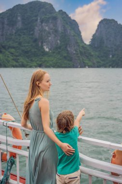Anne ve oğul gezginleri Halong Körfezi 'nde tekneyle seyahat ediyorlar. Vietnam. Asya 'ya seyahat, mutluluk duygusu, yaz tatili konsepti. Çocuk konseptiyle seyahat etmek. Ölüm nedeni 19 'dan sonra. Resimli deniz manzarası