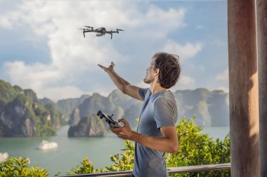 Halong Körfezi 'nde insansız hava aracını kontrol eden adam. Vietnam. Asya 'ya seyahat, mutluluk duygusu, yaz tatili konsepti. Resimli deniz manzarası. Ha Long Körfezi, Vietnam