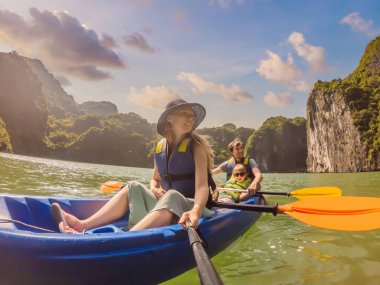 Anne, baba ve oğul Halong Körfezi 'nde kano üzerinde kürek çekiyorlar. Vietnam. Asya 'ya seyahat, mutluluk duygusu, yaz tatili konsepti. Çocuk konseptiyle seyahat etmek. Ölüm nedeni 19 'dan sonra. Resimli deniz.