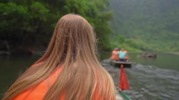 在越南北部的一个旅游胜地宁滨，一名年轻女子在一条河里漂流在壮观的石灰岩中，慢镜头拍下了她的照片。前往越南的旅行概念 — 图库视频影像