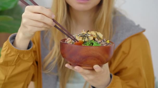 Eine junge Frau genießt ihr Abendessen in einem schönen Café, in dem Poke Bowls serviert werden. Schnell und gesund. Trendiges Food-Konzept — Stockvideo