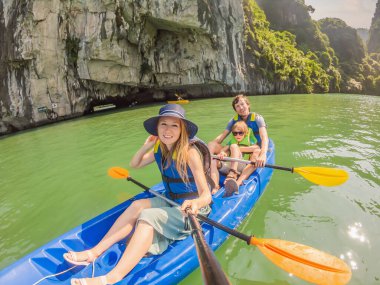 Anne, baba ve oğul Halong Körfezi 'nde kano üzerinde kürek çekiyorlar. Vietnam. Asya 'ya seyahat, mutluluk duygusu, yaz tatili konsepti. Çocuk konseptiyle seyahat etmek. Ölüm nedeni 19 'dan sonra. Resimli deniz.